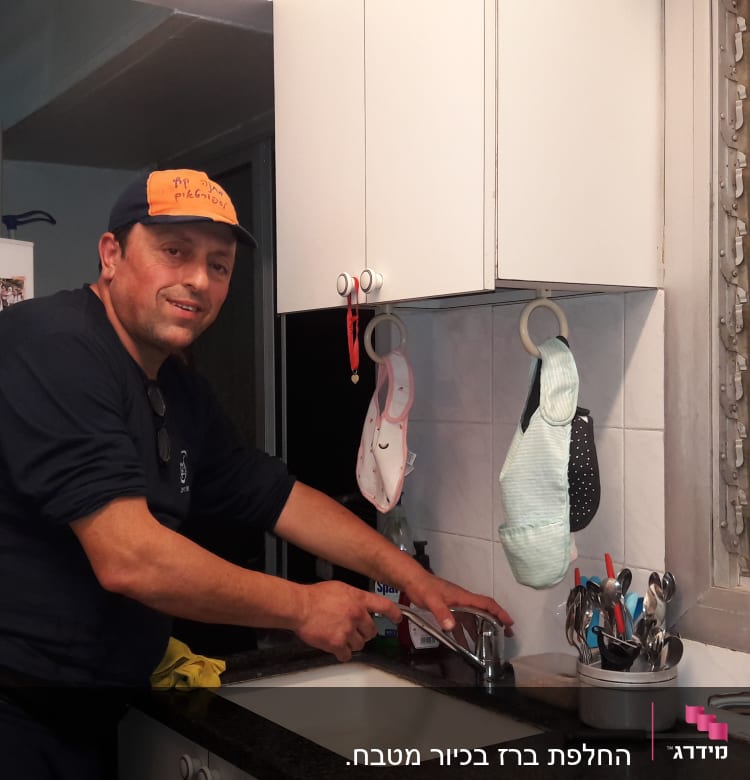 אדם מתקן ברז במטבח עם כלים